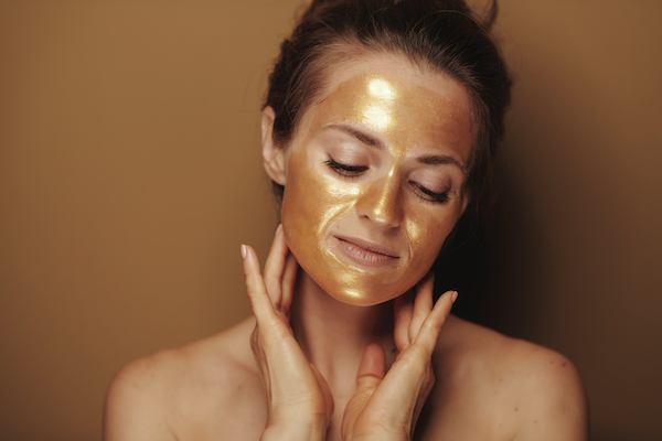 relaxed woman with golden mask against beige background